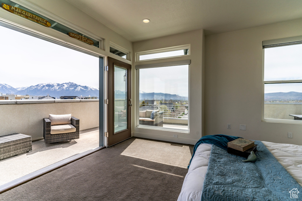 Carpeted bedroom featuring a mountain view, access to exterior, and multiple windows