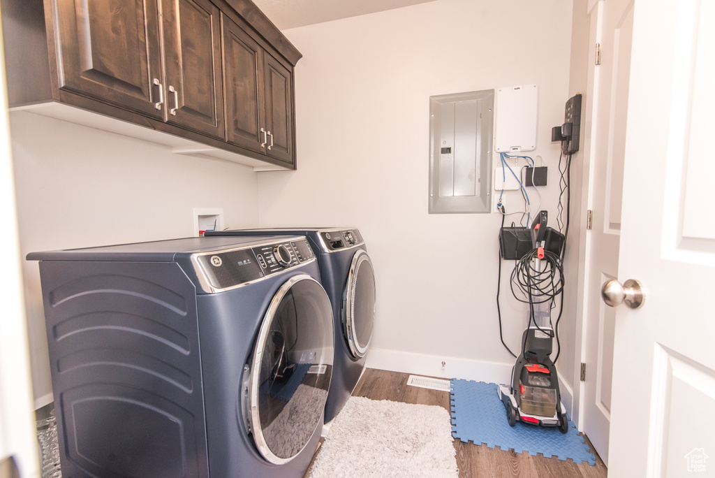 Clothes washing area featuring wood-type flooring, cabinets, hookup for a washing machine, and washer and clothes dryer