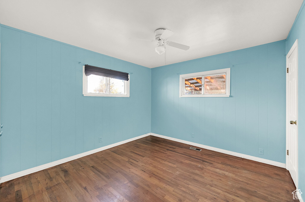 Spare room featuring dark wood-type flooring and ceiling fan
