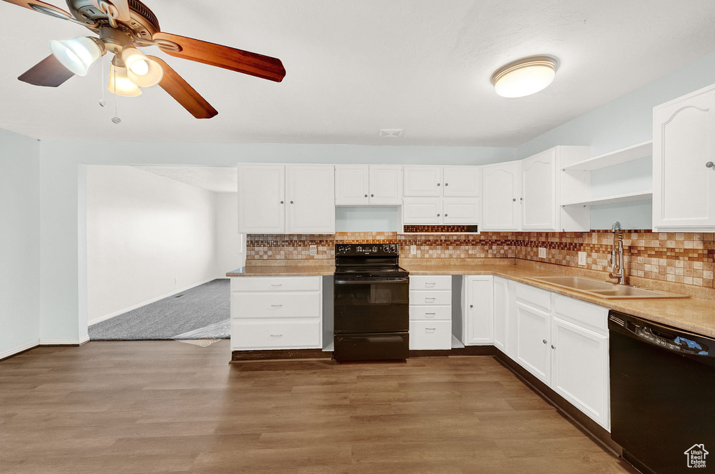 Kitchen featuring ceiling fan, black appliances, tasteful backsplash, dark wood-type flooring, and white cabinets