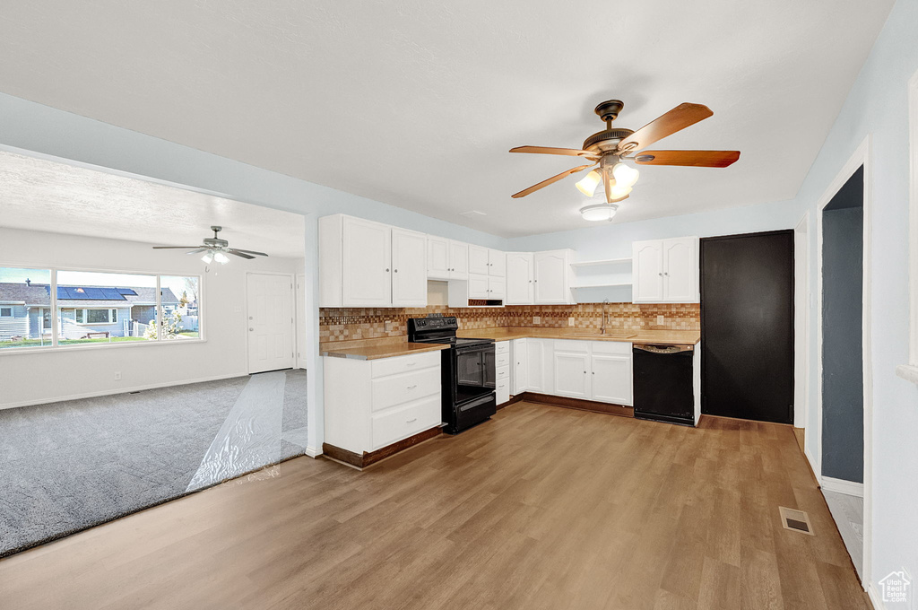 Kitchen with white cabinetry, light hardwood / wood-style flooring, black appliances, and backsplash