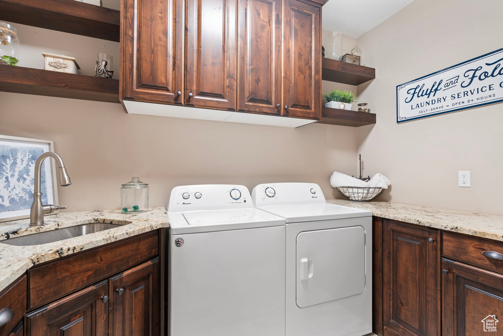 Clothes washing area with sink, cabinets, and washer and clothes dryer