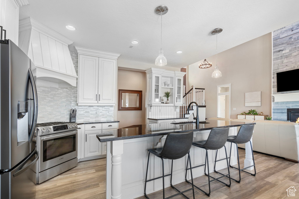 Kitchen featuring pendant lighting, light hardwood / wood-style floors, stainless steel appliances, and white cabinets