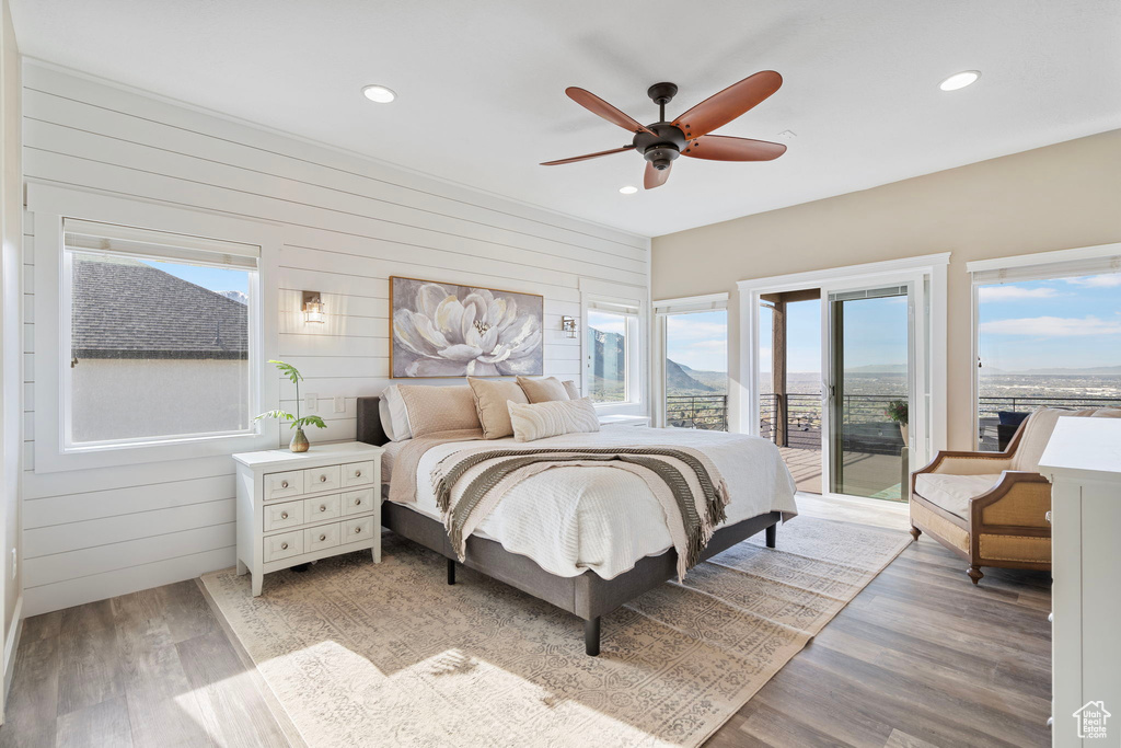 Bedroom with ceiling fan, light hardwood / wood-style floors, access to exterior, and multiple windows