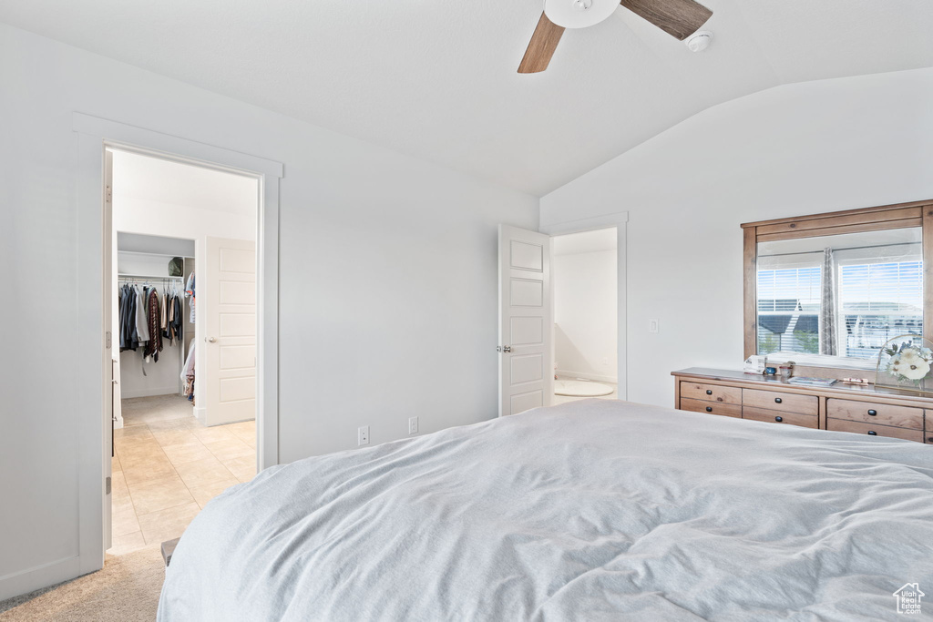 Bedroom featuring a closet, ceiling fan, light tile floors, a spacious closet, and vaulted ceiling