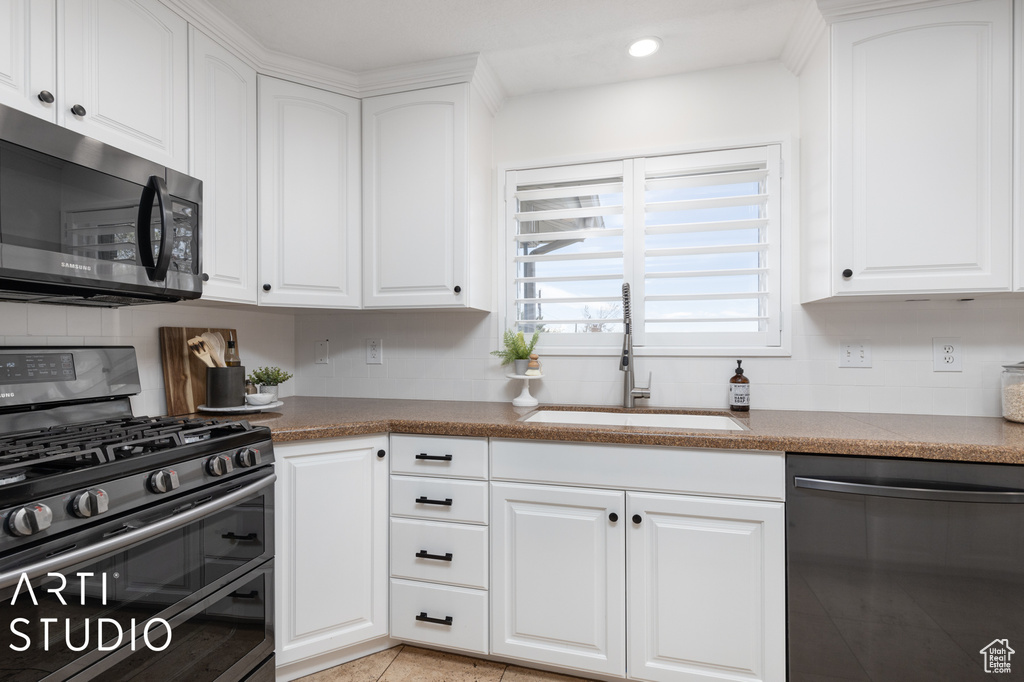 Kitchen with double oven range, dishwasher, light tile flooring, white cabinets, and sink