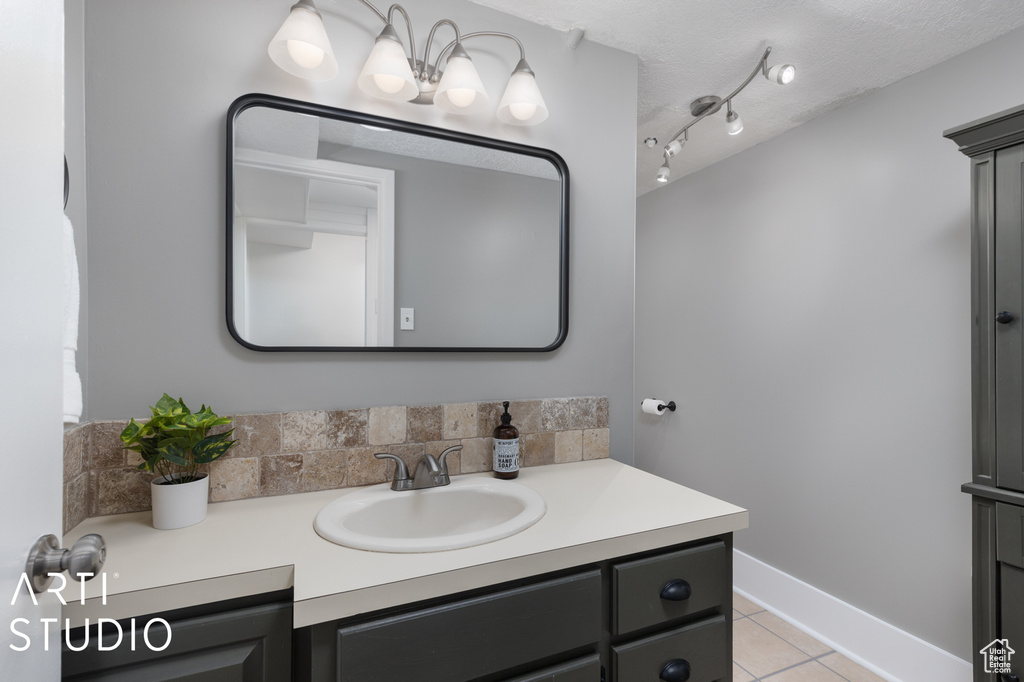 Bathroom with large vanity, track lighting, a textured ceiling, tasteful backsplash, and tile floors