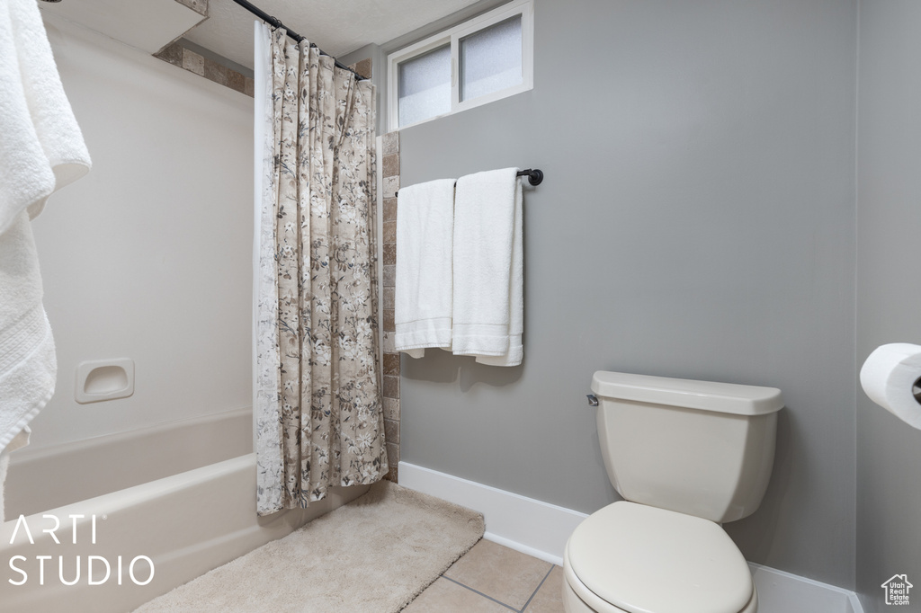 Bathroom with shower / tub combo, tile floors, and toilet