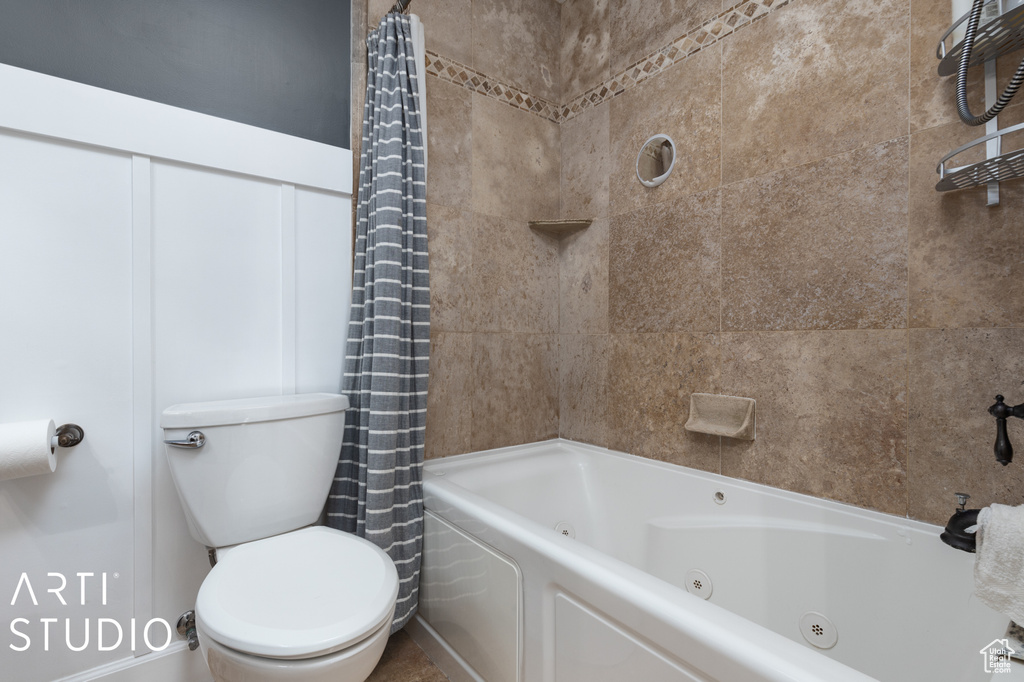 Bathroom featuring toilet and shower / tub combo with curtain