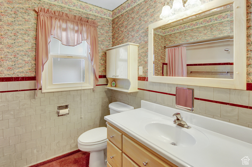 Bathroom with tile walls, oversized vanity, and toilet