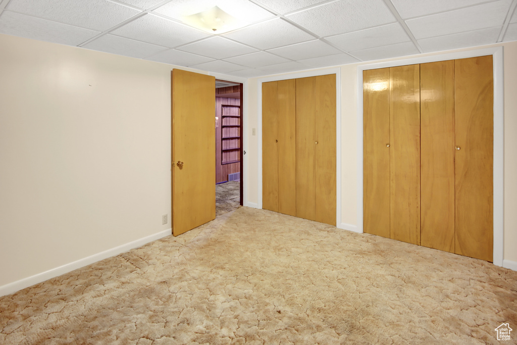 Basement with light colored carpet and a drop ceiling
