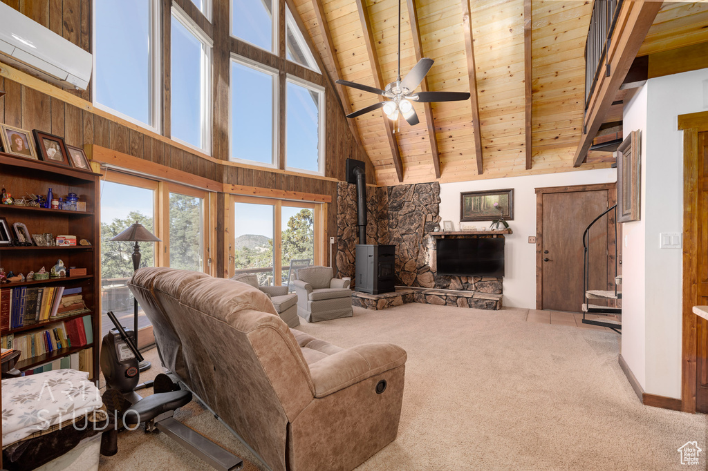 Carpeted living room featuring high vaulted ceiling, ceiling fan, a wood stove, and wood ceiling