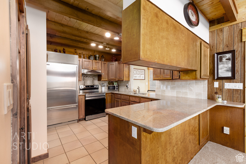 Kitchen featuring light tile floors, tasteful backsplash, beam ceiling, stainless steel appliances, and kitchen peninsula