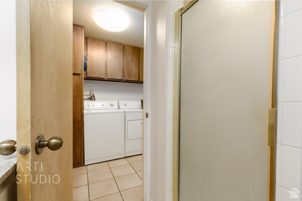 Washroom featuring cabinets, light tile floors, and washer and clothes dryer