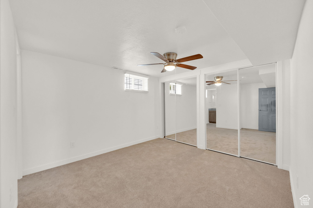 Unfurnished bedroom with light carpet and ceiling fan