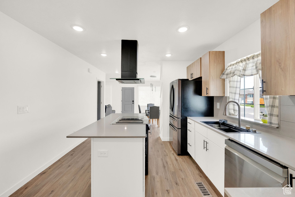 Kitchen with white cabinetry, sink, stainless steel dishwasher, island exhaust hood, and light hardwood / wood-style floors