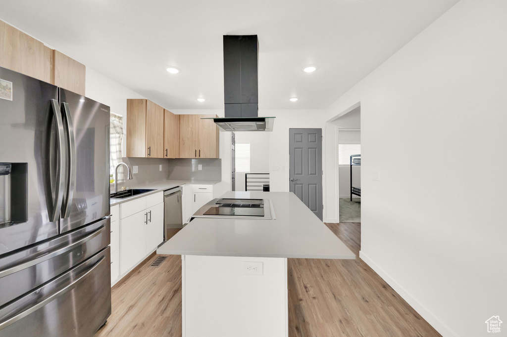 Kitchen featuring a center island, light wood-type flooring, island range hood, light brown cabinetry, and appliances with stainless steel finishes