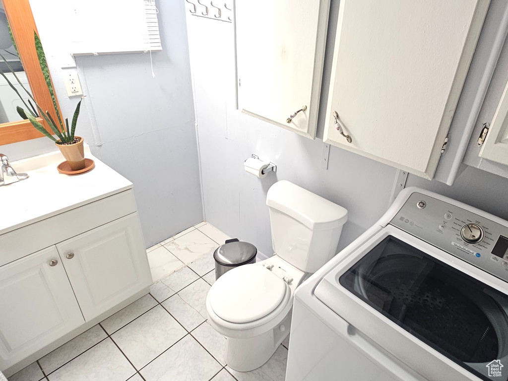 Bathroom with toilet, washer / clothes dryer, sink, and tile flooring