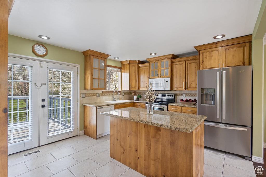 Kitchen with appliances with stainless steel finishes, backsplash, plenty of natural light, and light stone countertops
