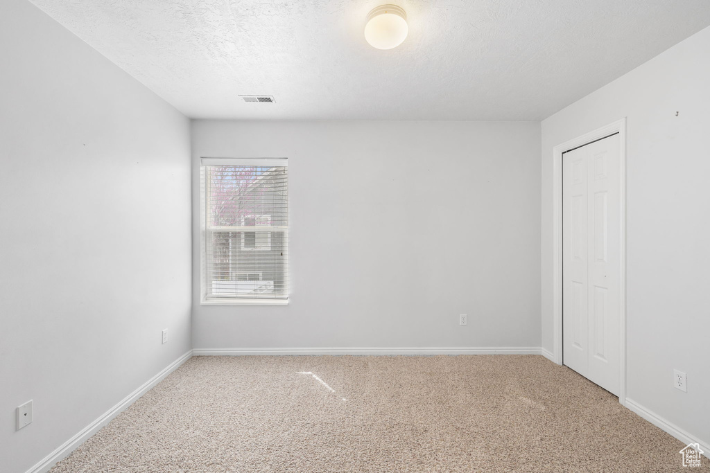 Unfurnished room featuring light carpet and a textured ceiling