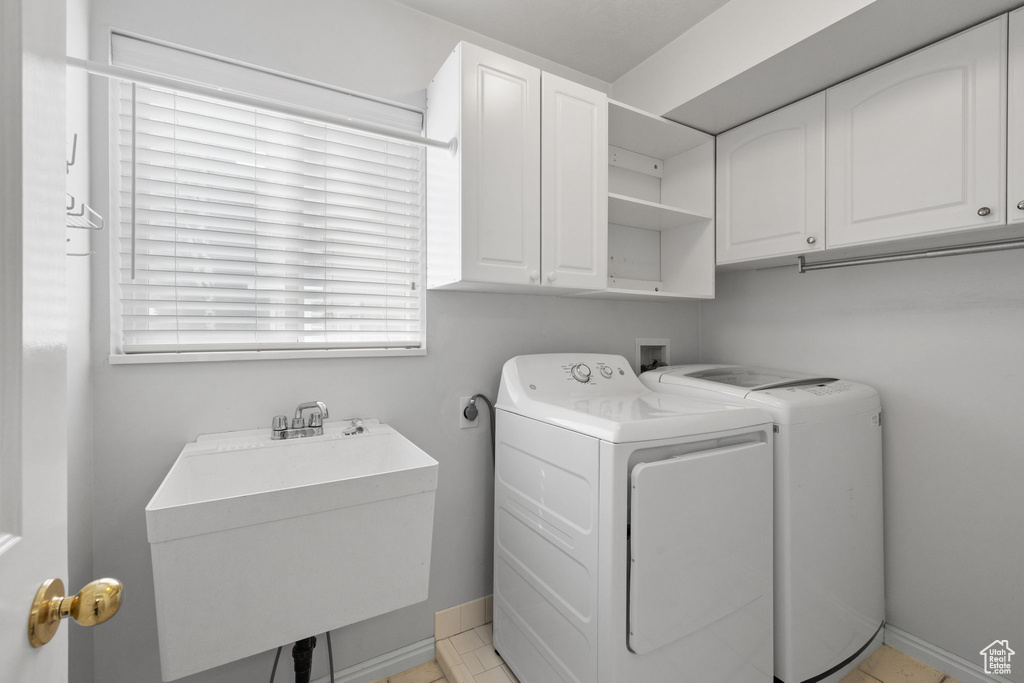 Laundry area featuring washer and clothes dryer, electric dryer hookup, light tile floors, sink, and cabinets