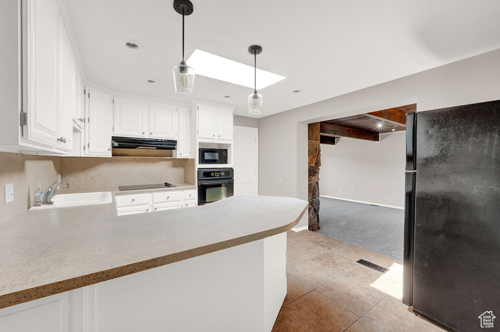 Kitchen with ventilation hood, black appliances, white cabinets, sink, and pendant lighting