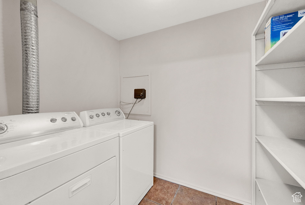 Clothes washing area featuring independent washer and dryer and dark tile floors