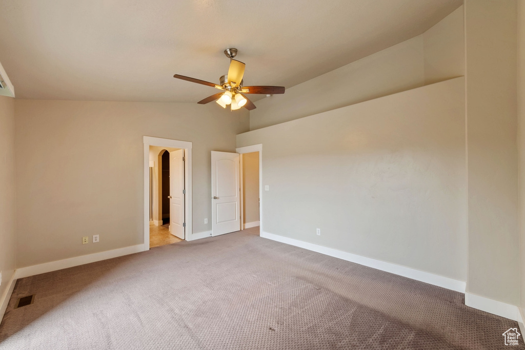 Carpeted spare room featuring ceiling fan and lofted ceiling