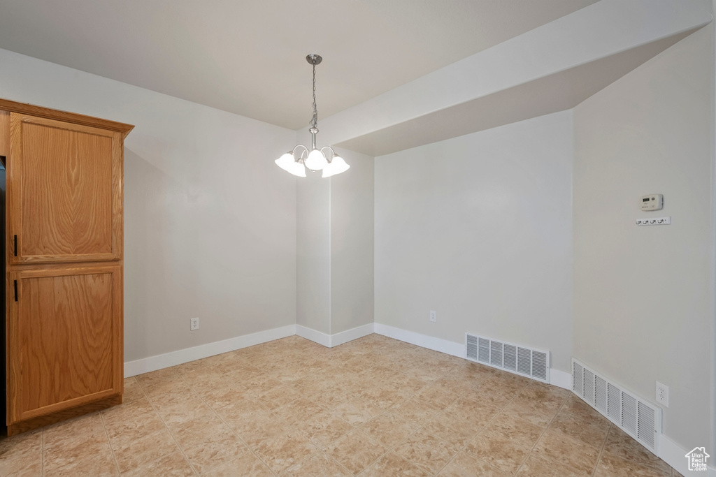Empty room with an inviting chandelier and light tile flooring