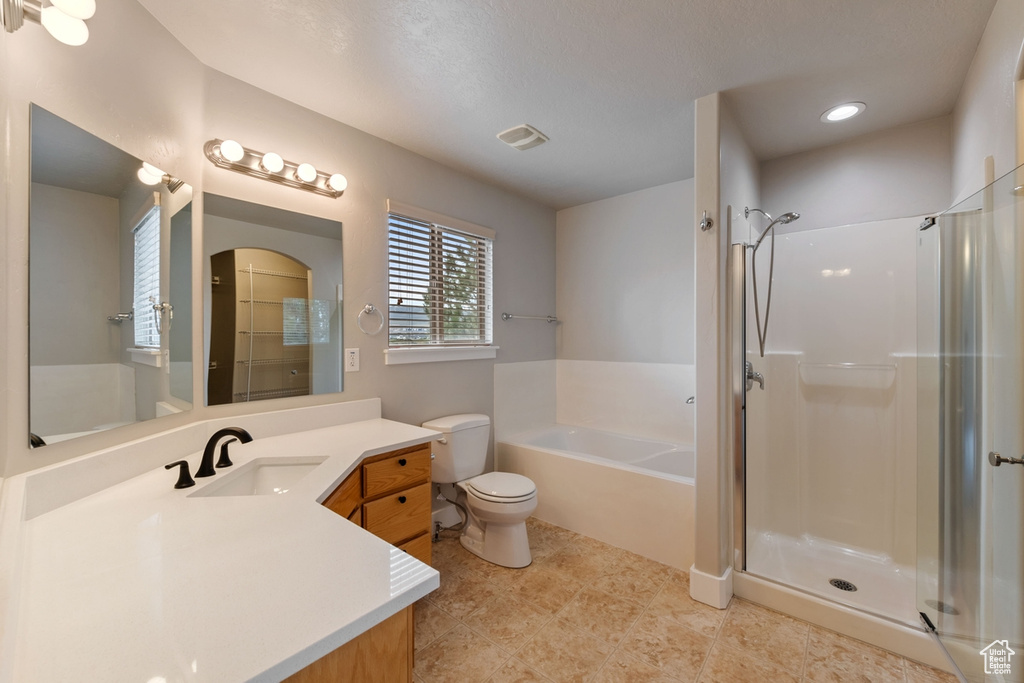 Full bathroom with independent shower and bath, vanity, tile floors, and toilet