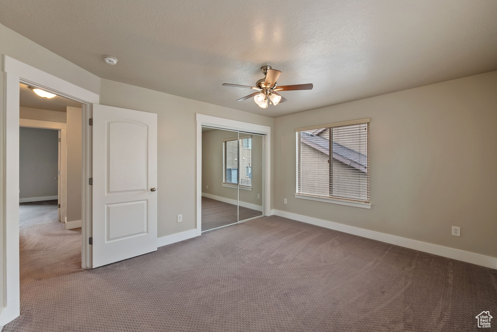 Unfurnished bedroom featuring ceiling fan and dark carpet
