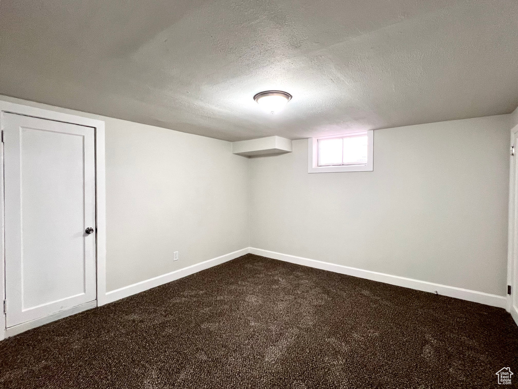 Basement featuring a textured ceiling and dark carpet