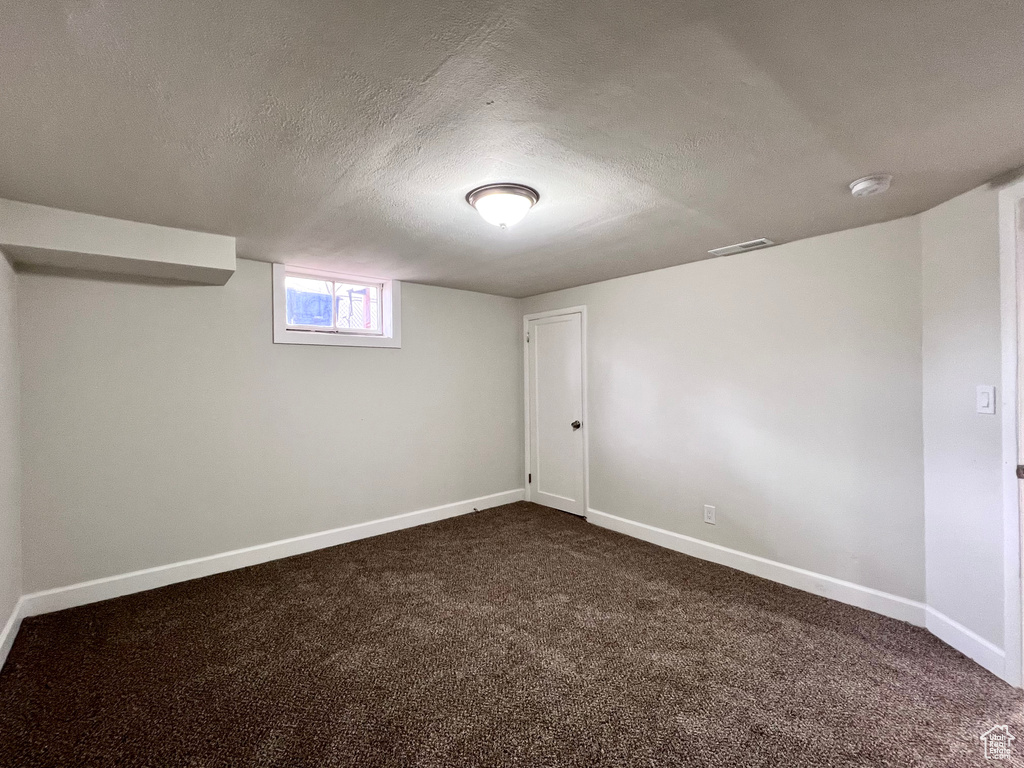Basement with dark carpet and a textured ceiling