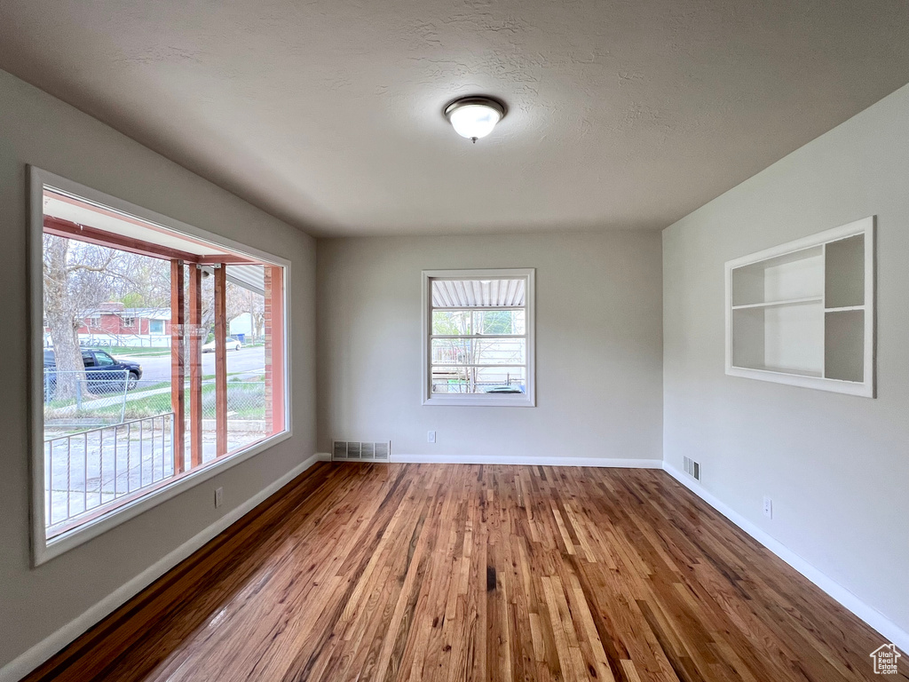 Empty room featuring a healthy amount of sunlight and hardwood / wood-style flooring
