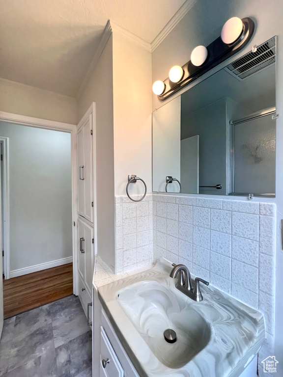 Bathroom with backsplash, crown molding, oversized vanity, and hardwood / wood-style floors