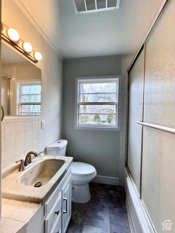 Full bathroom with oversized vanity, toilet, tile flooring, tasteful backsplash, and shower / bath combination with glass door