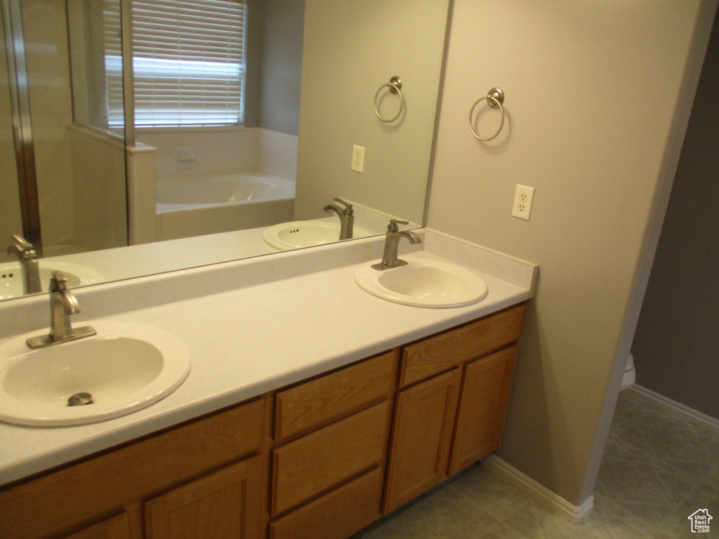 Bathroom featuring dual bowl vanity, a bathing tub, and tile flooring