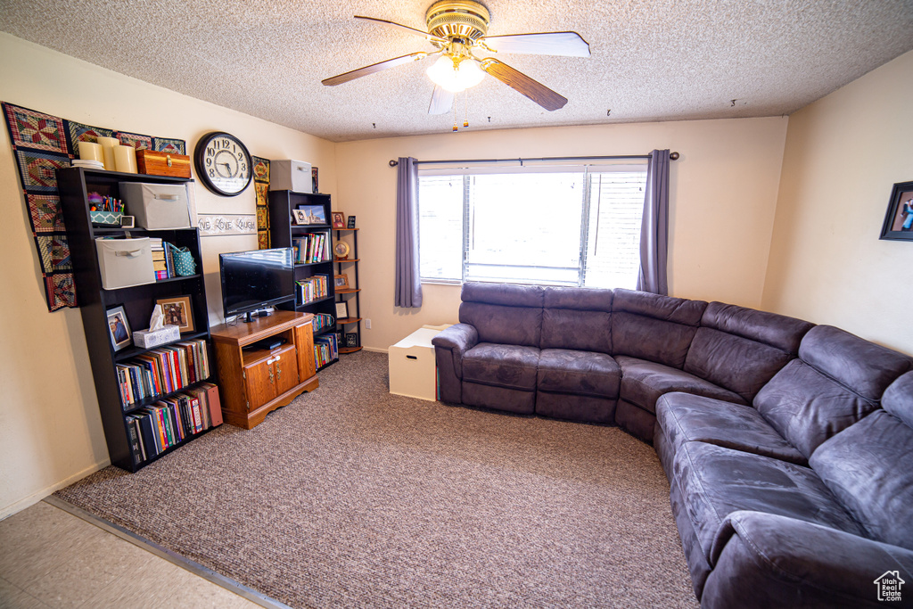 Living room featuring carpet, ceiling fan, and a textured ceiling