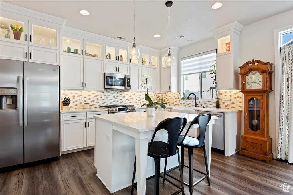Kitchen featuring a center island, tasteful backsplash, stainless steel appliances, and dark hardwood / wood-style floors