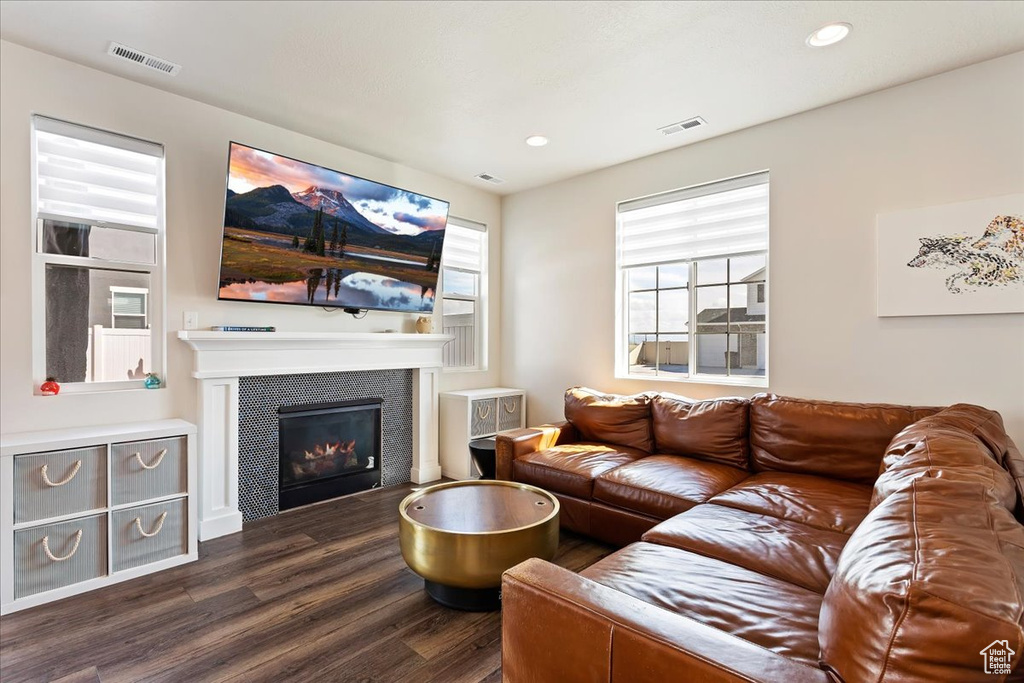 Living room with dark hardwood / wood-style flooring and a tile fireplace