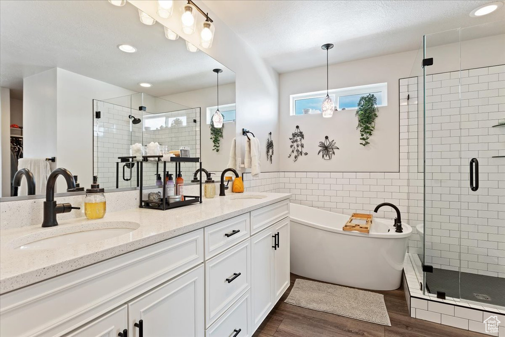 Bathroom with wood-type flooring, large vanity, independent shower and bath, and double sink