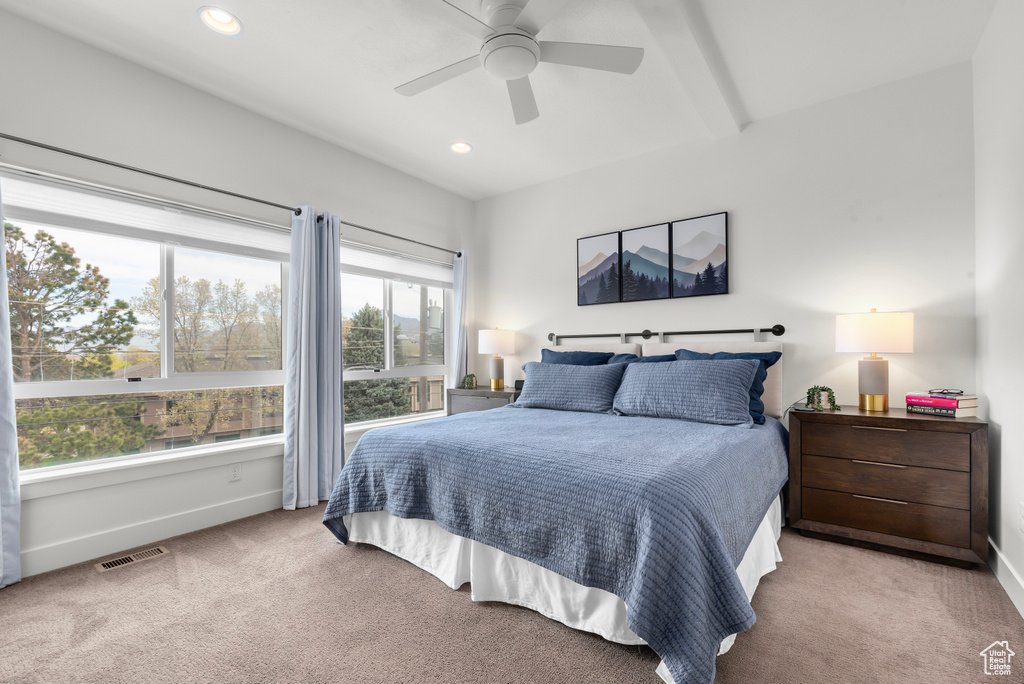 Carpeted bedroom featuring beam ceiling and ceiling fan