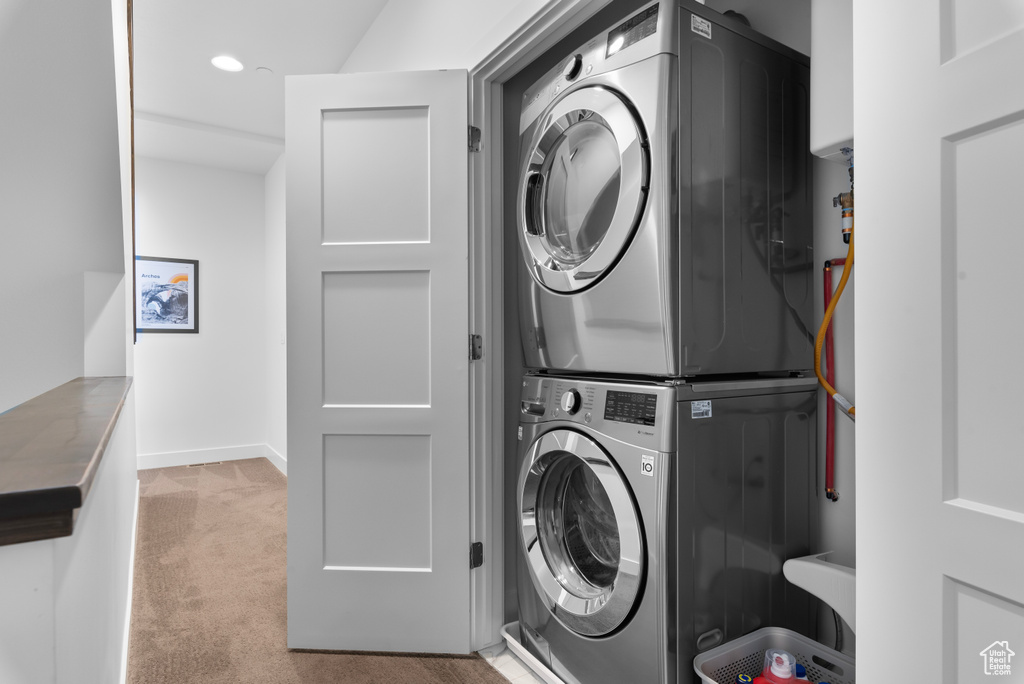 Laundry room with light colored carpet and stacked washer and clothes dryer