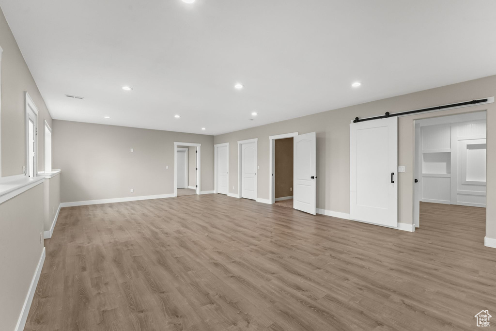 Unfurnished room with light hardwood / wood-style flooring and a barn door