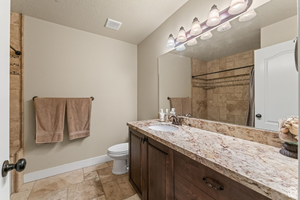 Bathroom featuring toilet, tile floors, vanity, and a textured ceiling