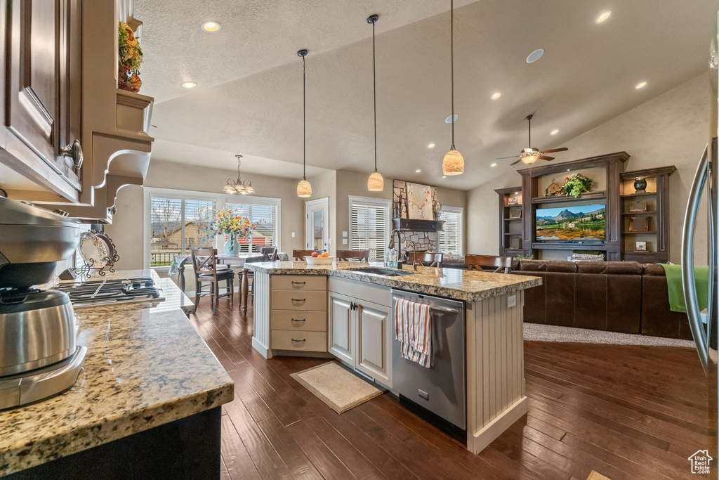 Kitchen featuring dark hardwood / wood-style floors, pendant lighting, light stone counters, and stainless steel dishwasher