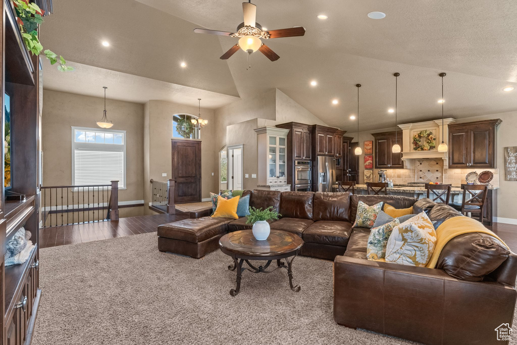 Living room featuring high vaulted ceiling, ceiling fan with notable chandelier, and hardwood / wood-style flooring