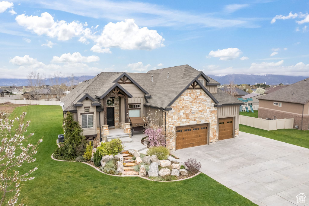 Craftsman-style home with a garage, a mountain view, and a front lawn