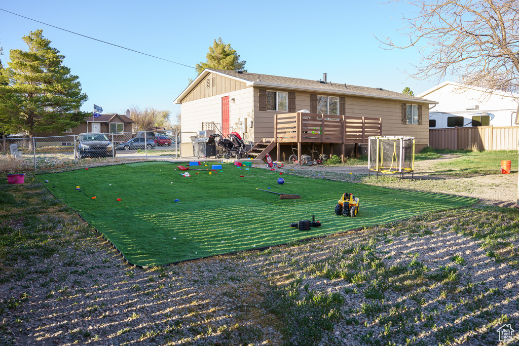 Back of property featuring a wooden deck and a lawn