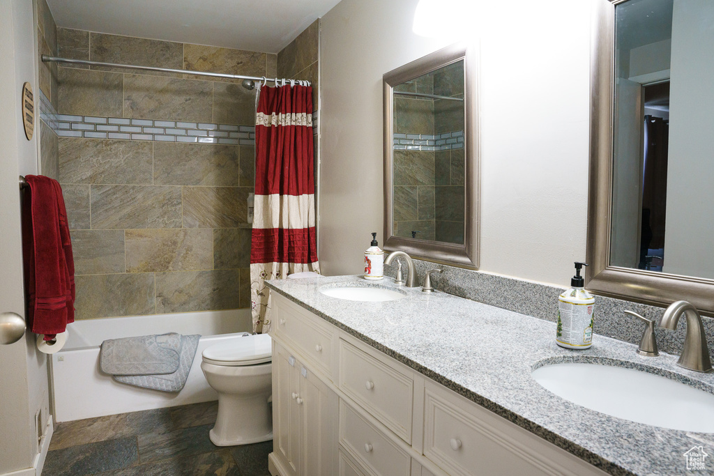 Full bathroom featuring dual bowl vanity, toilet, tile floors, and shower / tub combo with curtain